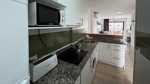 A modern kitchen with a microwave, toaster, sink, and washing machine. - Sa Gavina C, 2 Bedroom apartment with WIFI, POOL, LIFT, balcony or terace. (L'Estartit)
