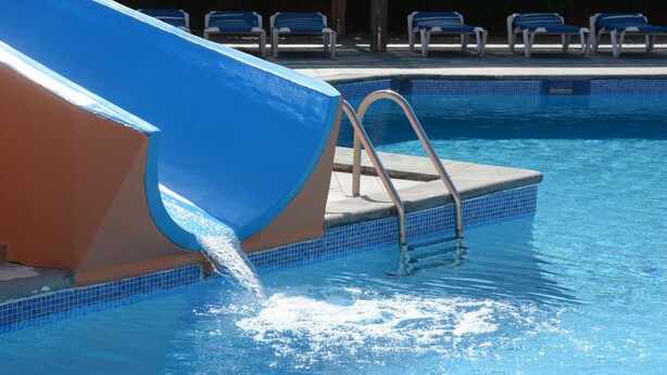 A swimming pool with a blue slide and a ladder leading into the water. - Sa Gavina C, 2 Bedroom apartment with WIFI, POOL, LIFT, balcony or terace. (L'Estartit)