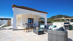 Un espace extérieur aménagé avec des meubles en osier, un barbecue et une vue sur une montagne.