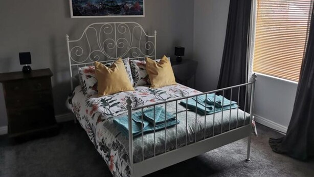 Ein Schlafzimmer mit einem Metallbettgestell, floralem Bettzeug und einem Stadtbild an der Wand.