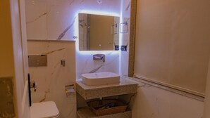 Une petite salle de bain avec un lavabo blanc, un miroir et des toilettes.