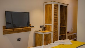 Une chambre à coucher comprenant un lit, une télévision, une armoire en bois et une petite table avec une bouilloire.