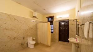 A bathroom with a toilet, shower, and sink.