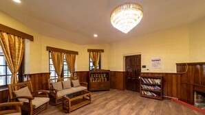 A spacious living room with wooden furniture, a chandelier, and a fireplace.