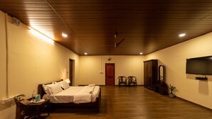 Une chambre d’hôtel avec un lit, une table de chevet, une lampe et un téléviseur fixé au mur.