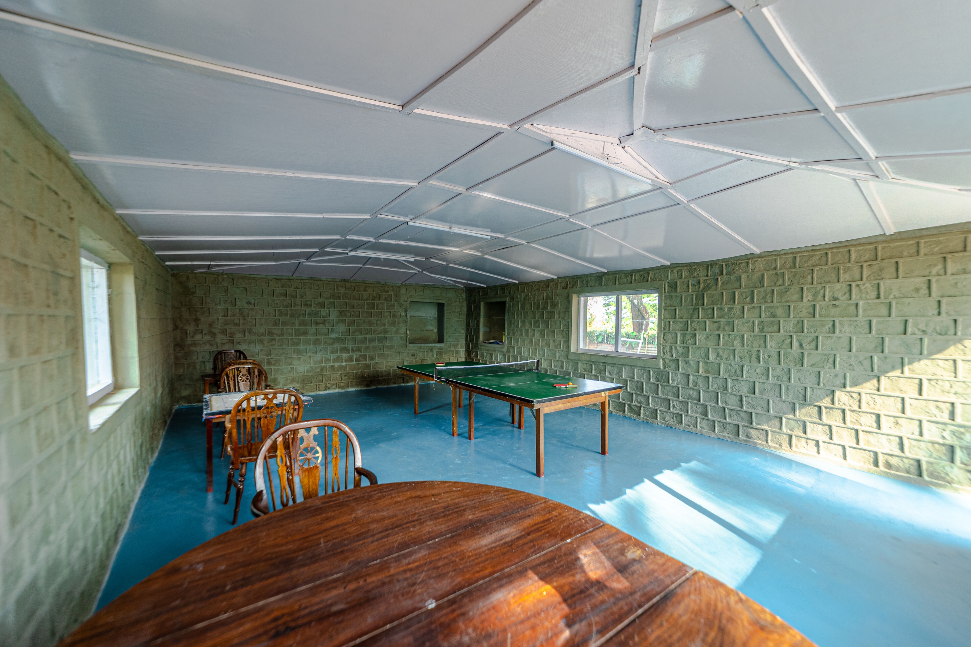 Una habitación con mesa de ping pong, sillas y mesa de billar.