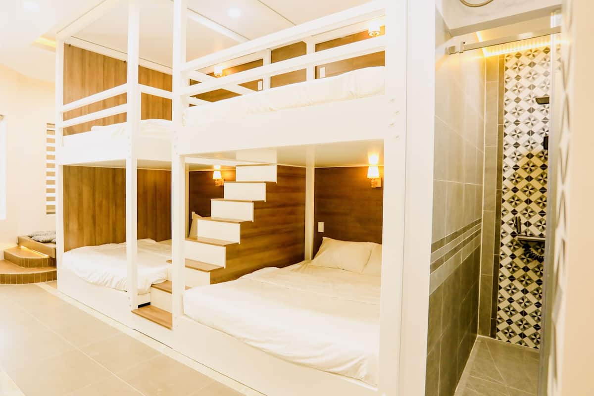 Quarto com beliches, área de chuveiro e parede com padrão.