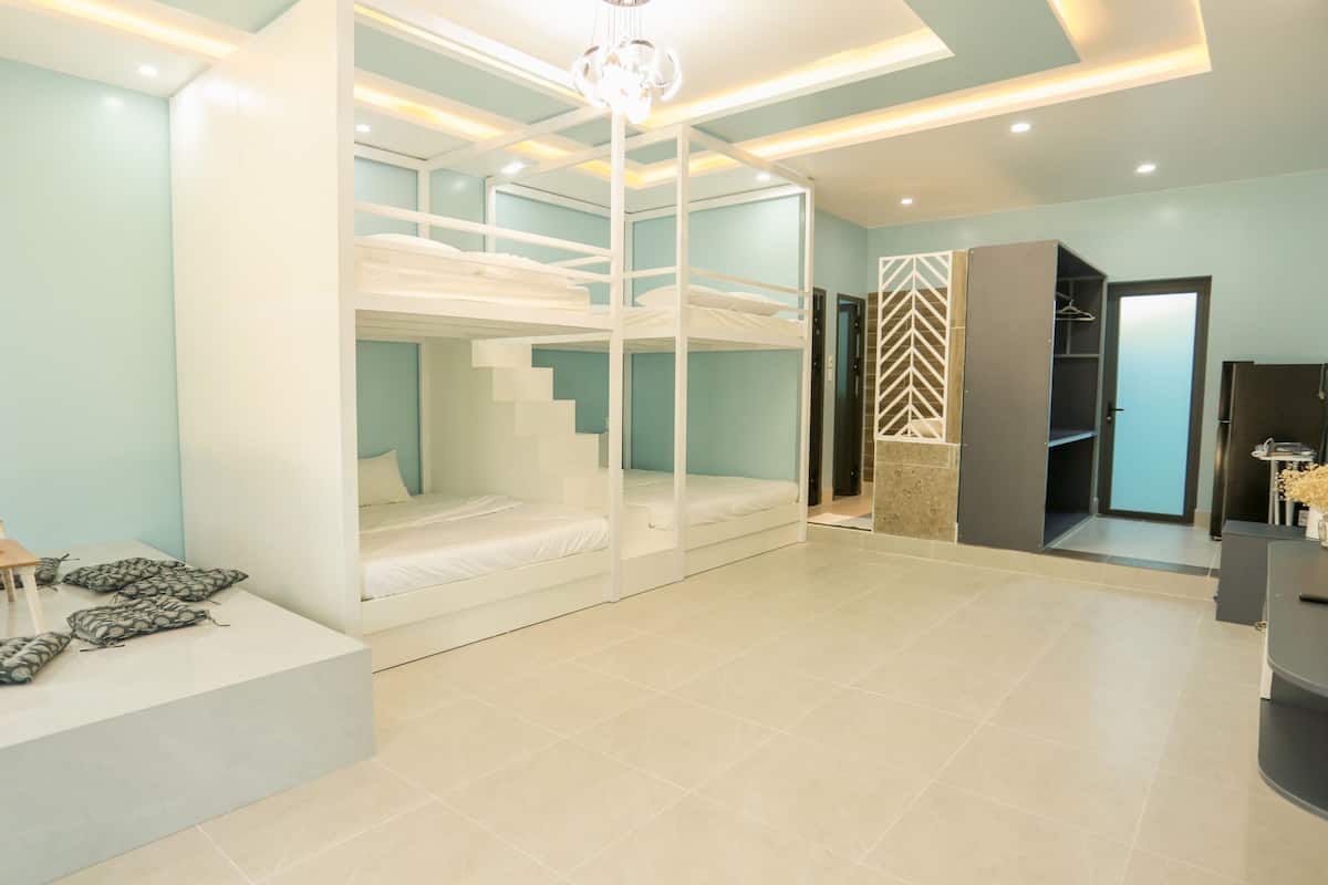 Quarto de hotel moderno com beliches, uma mesinha com um vaso e um espelho.