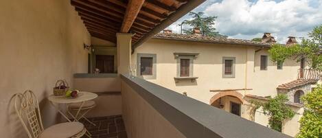A balcony with a table and chairs, a view of buildings, and a tiled floor.