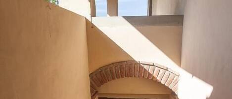 A staircase leading to a covered area with a potted plant and a window.