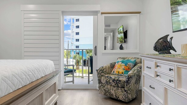 Une chambre à coucher avec un lit, une chaise, une commode et un téléviseur.