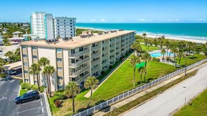 Un hôtel à plusieurs étages doté d’une piscine sur le toit, offrant une vue sur la plage et disposant d’un parking.