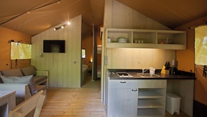 Una cocina compacta con un lavamanos, armarios y un televisor montado en la pared.