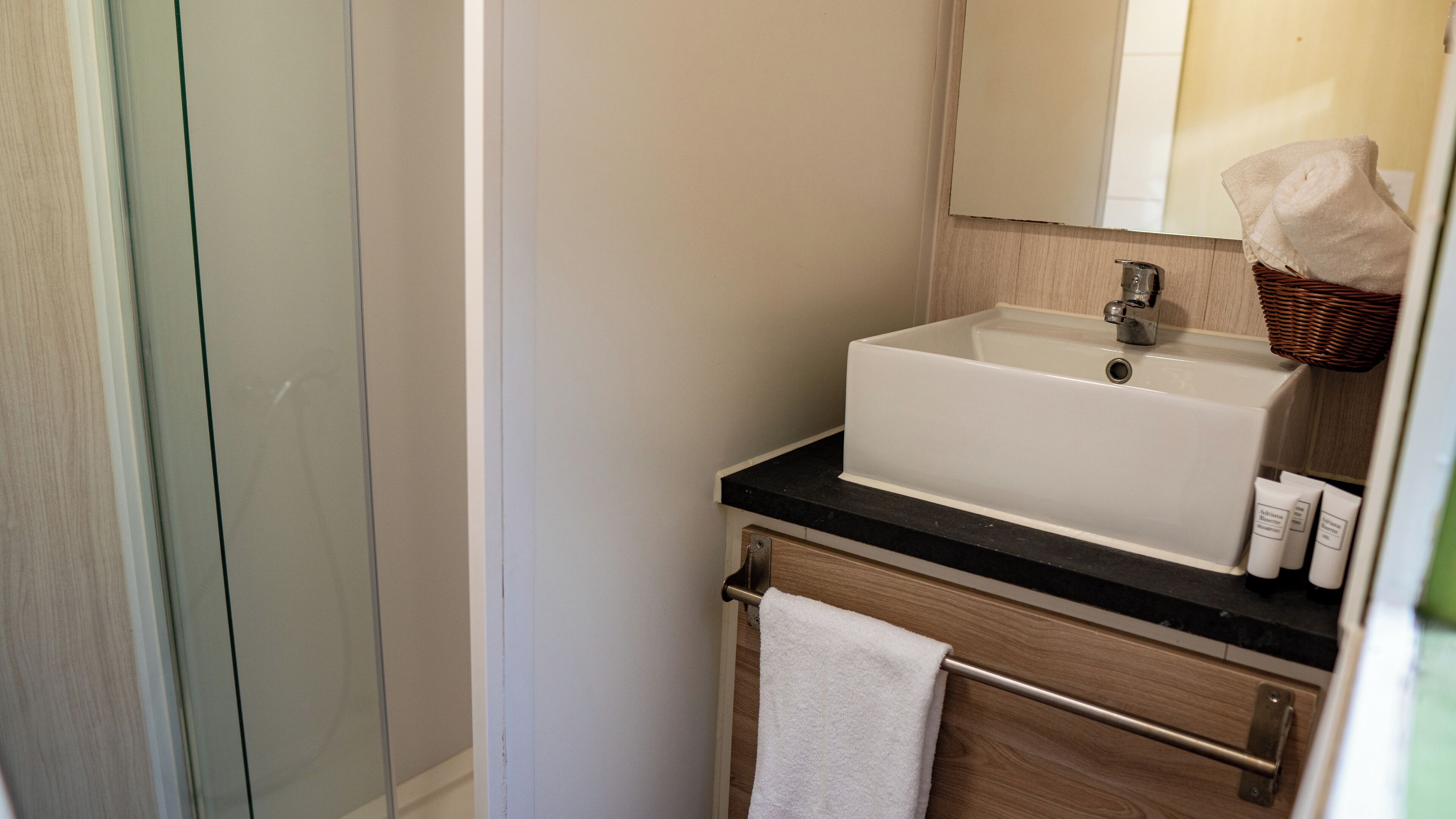 A bathroom with a white sink, a mirror, and a towel rack.