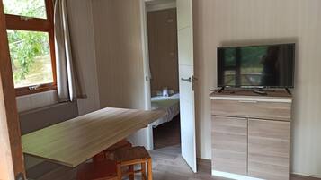 Una stanza compatta con una scrivania in legno, una televisione e un letto con vista sul verde.