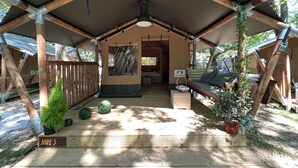A wooden cabin with a covered porch, a seating area with cushions, and a sign labeled "JARE 5". - Camping Etxarri (Etxarri-Aranatz)