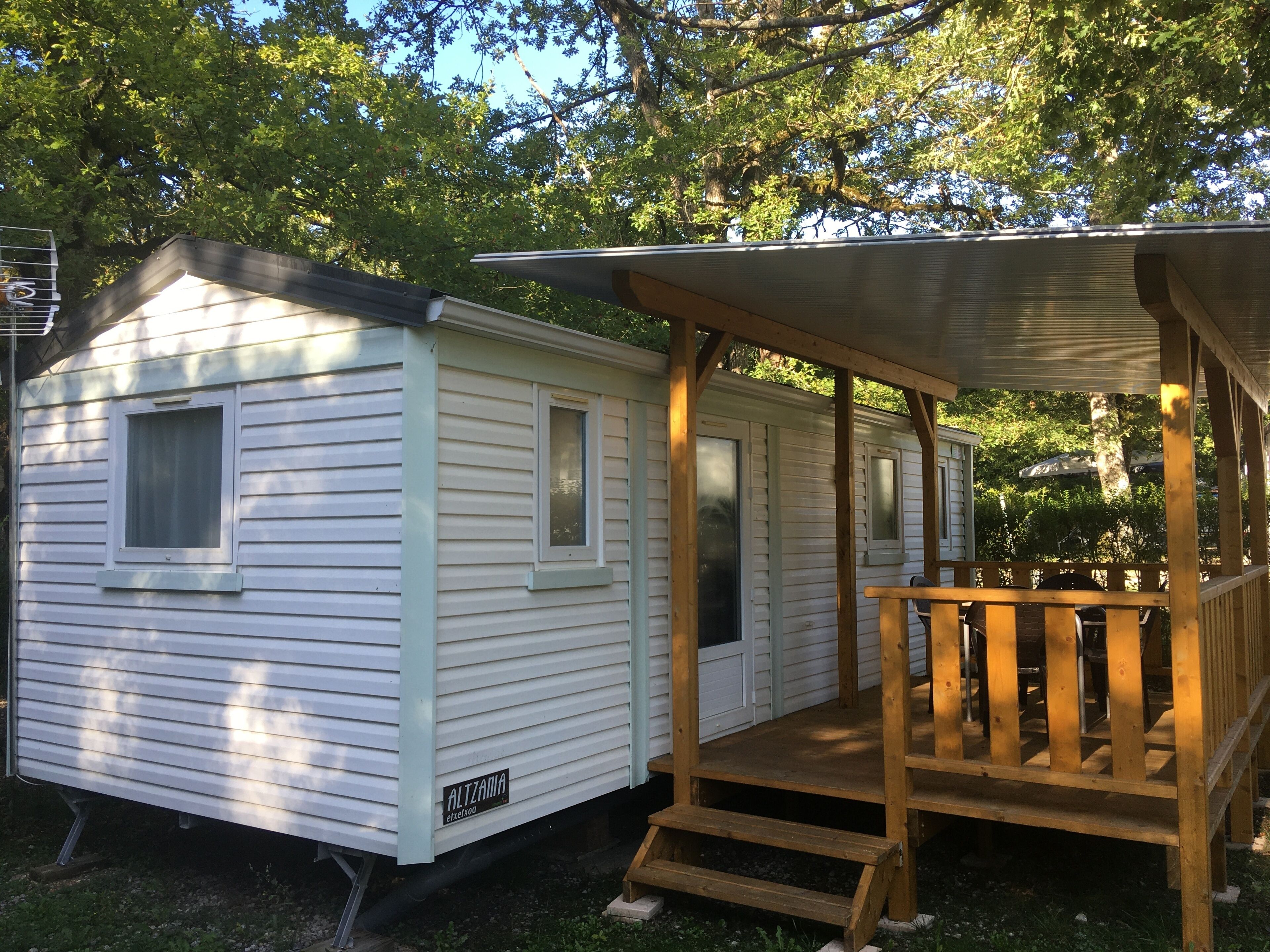 Une petite maison mobile d’un seul étage, dotée d’un porche et d’une petite terrasse.