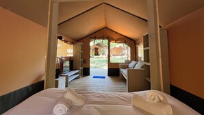 Una habitación con tienda de campaña, una cama, un escritorio y una silla.