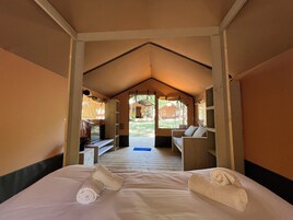 A tented room with a bed, a desk, and a chair.