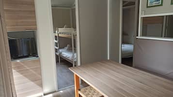 Een kleine kamer met een stapelbed, een bureau en een stoel.
