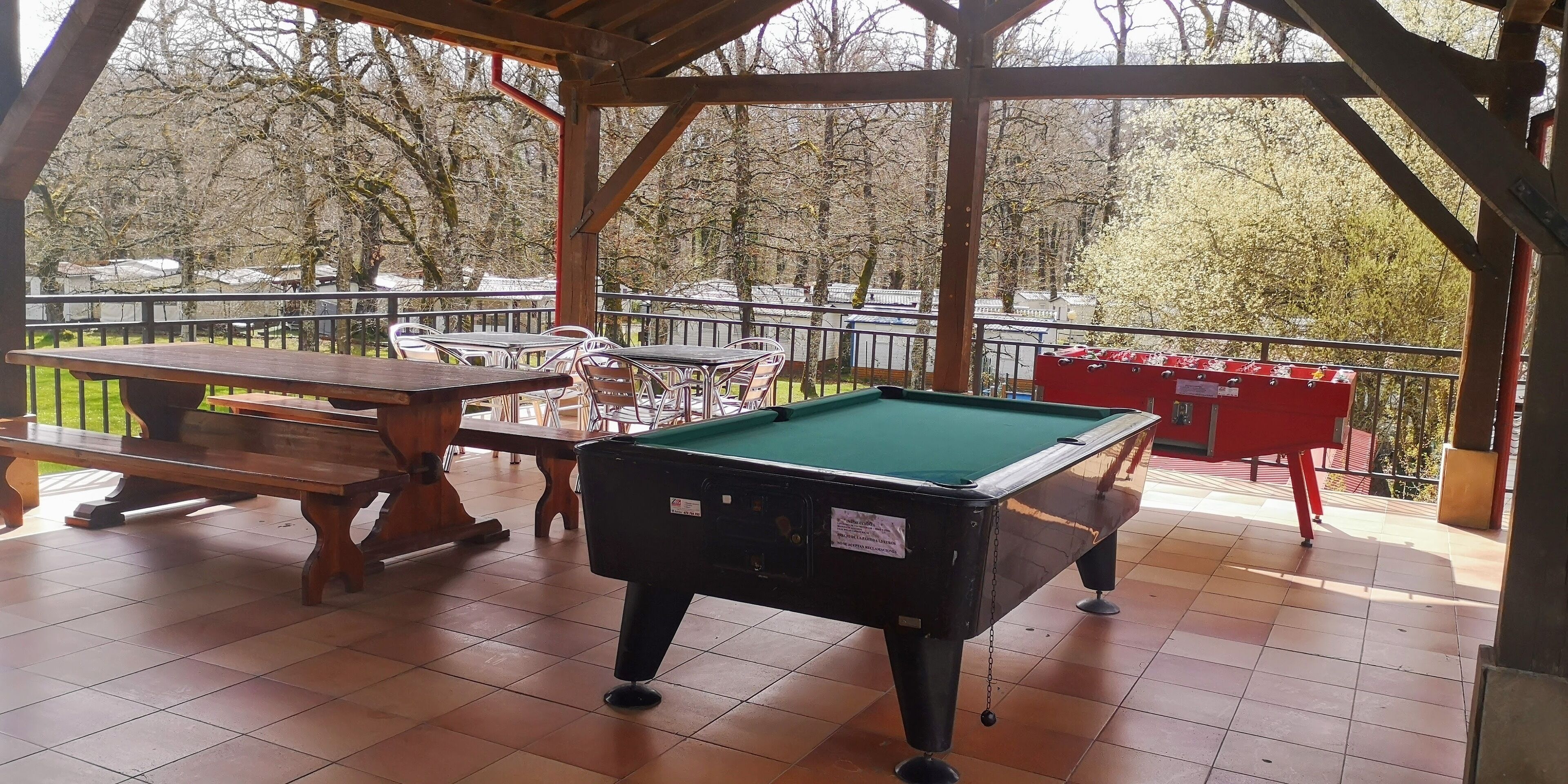 An indoor recreational area with a pool table, a billiards table, and a red table tennis table.