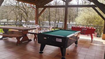 An indoor recreational area with a pool table, a billiards table, and a red table tennis table.