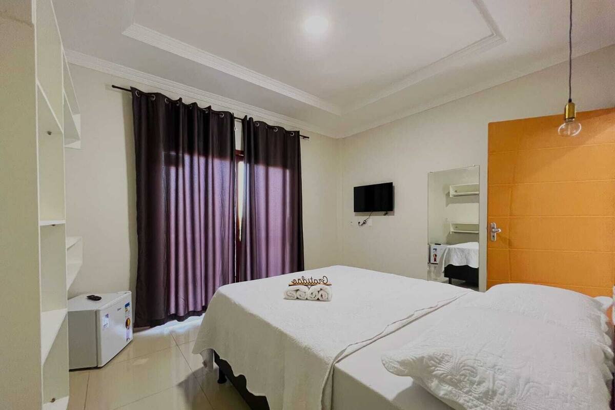 Una habitación de hotel con cama, televisor, espejo y puerta.