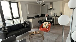 A modern living room with a sofa, armchair, and a coffee table with a basket.