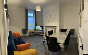 A modern living room with a sofa, TV, and dining table. - Stunning 3-bedroom in Rishton (Blackburn)