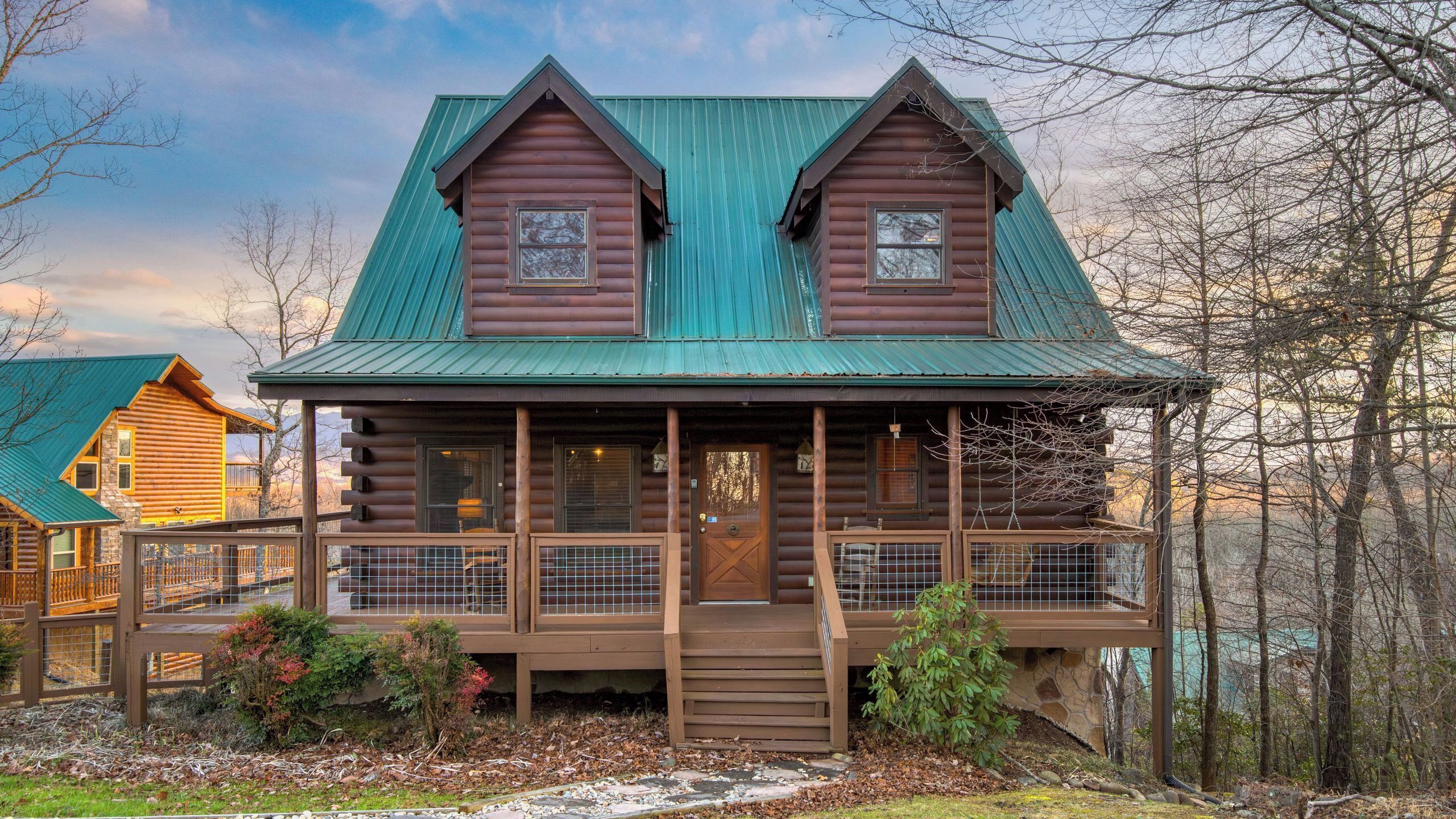 A log cabin with a porch, a front door, and a small staircase leading up to the entrance.