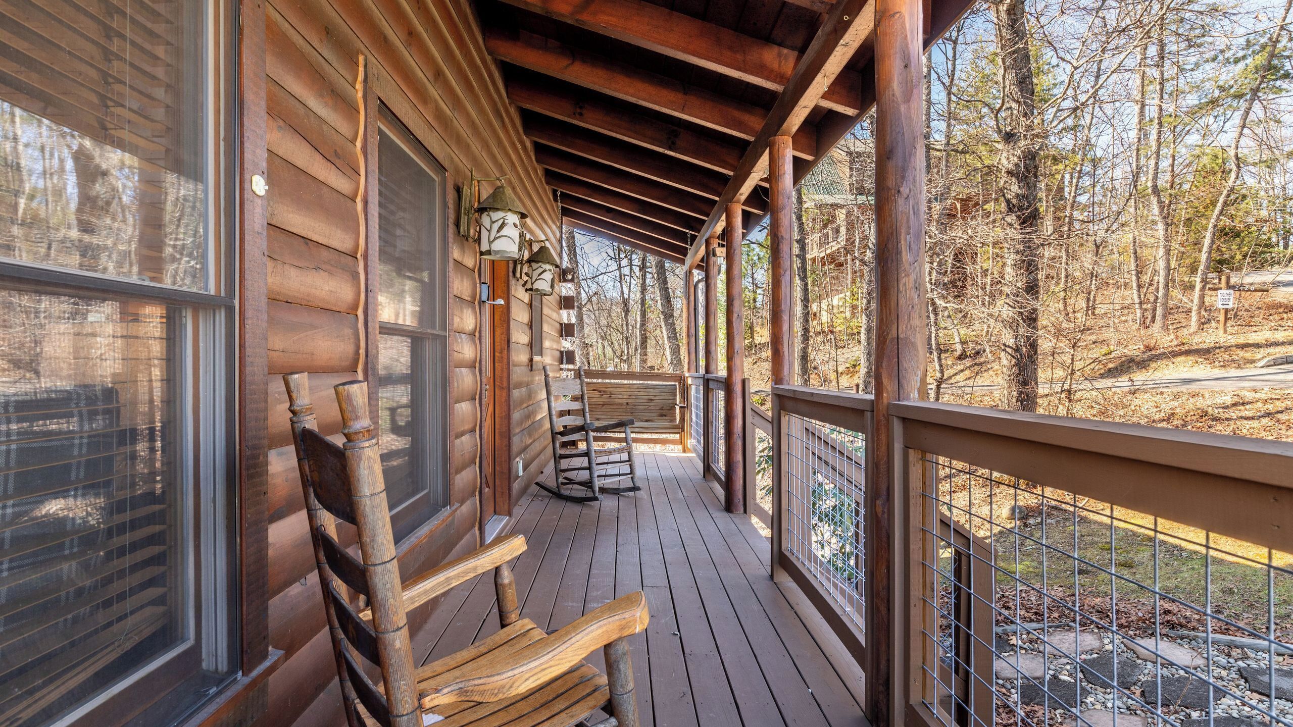 Une cabane en bois dotée d’une véranda, de fauteuils à bascule et offrant une vue sur la forêt environnante.