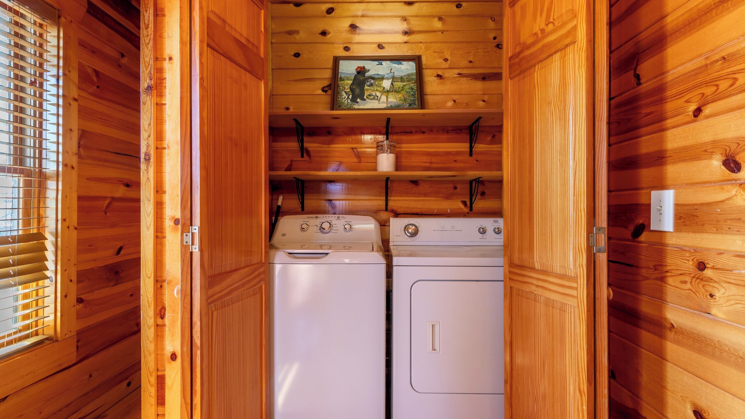 Interior de una cabaña de madera con lavandería que contiene dos lavadoras blancas.