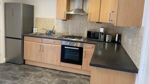 A modern kitchen with a stainless steel refrigerator, a gas stove, a microwave, and a toaster.