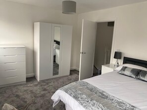 A bedroom with a bed, a wardrobe, a nightstand, and a lamp. - Home Sleeps5-netflix-parkg-near City Center/etihad (Manchester)