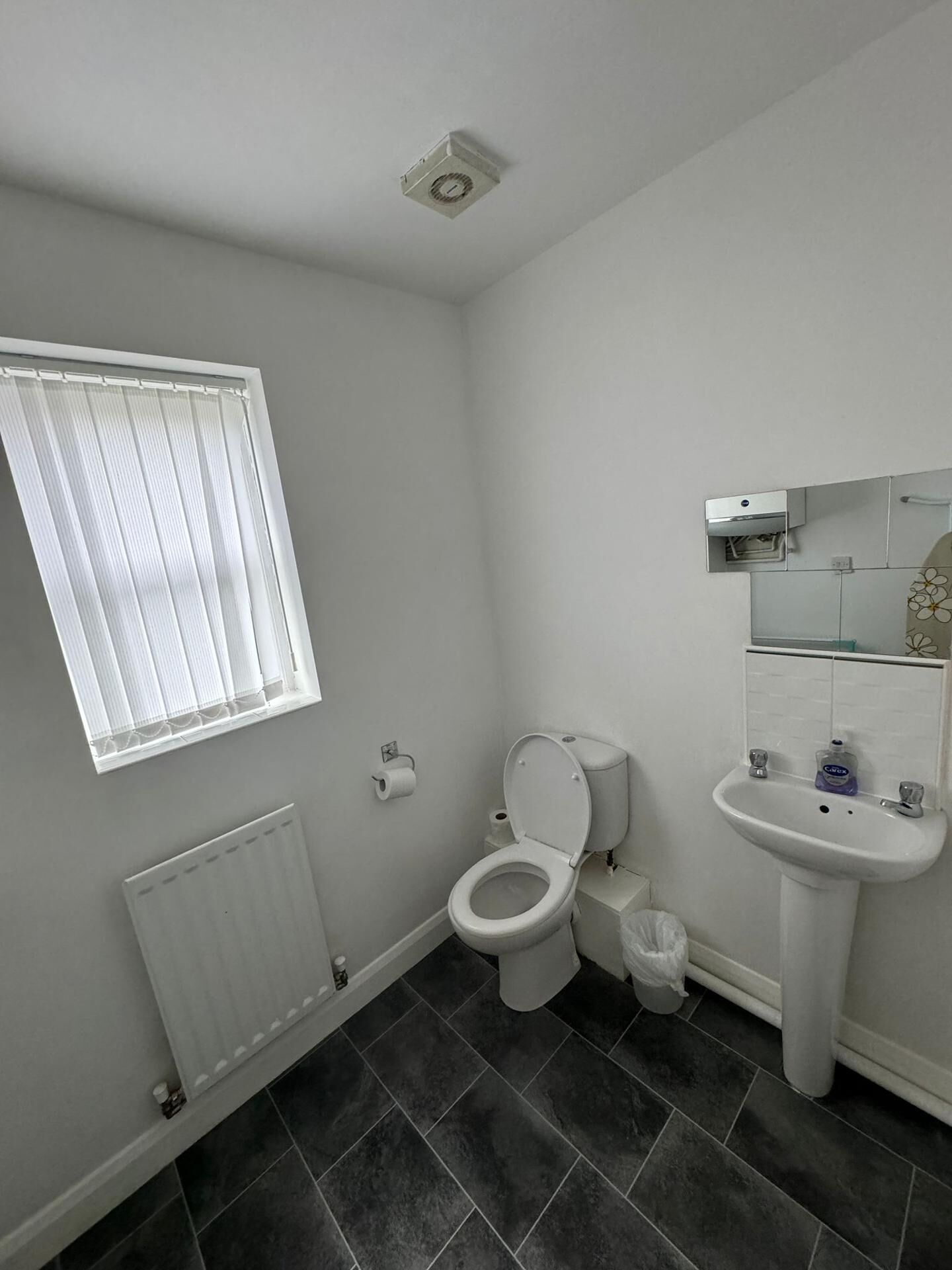 A small, modern bathroom with a toilet, sink, and window.