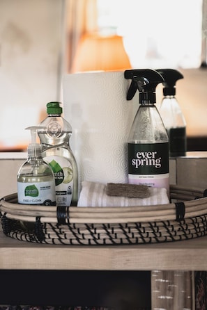 Una bandeja con productos de limpieza, incluyendo spray antibacterial EverSpring, un dispensador de jabón para manos y toallas de papel.