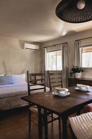 Une pièce chaleureuse avec une table à manger en bois, deux chaises, un canapé et une fenêtre avec des rideaux.