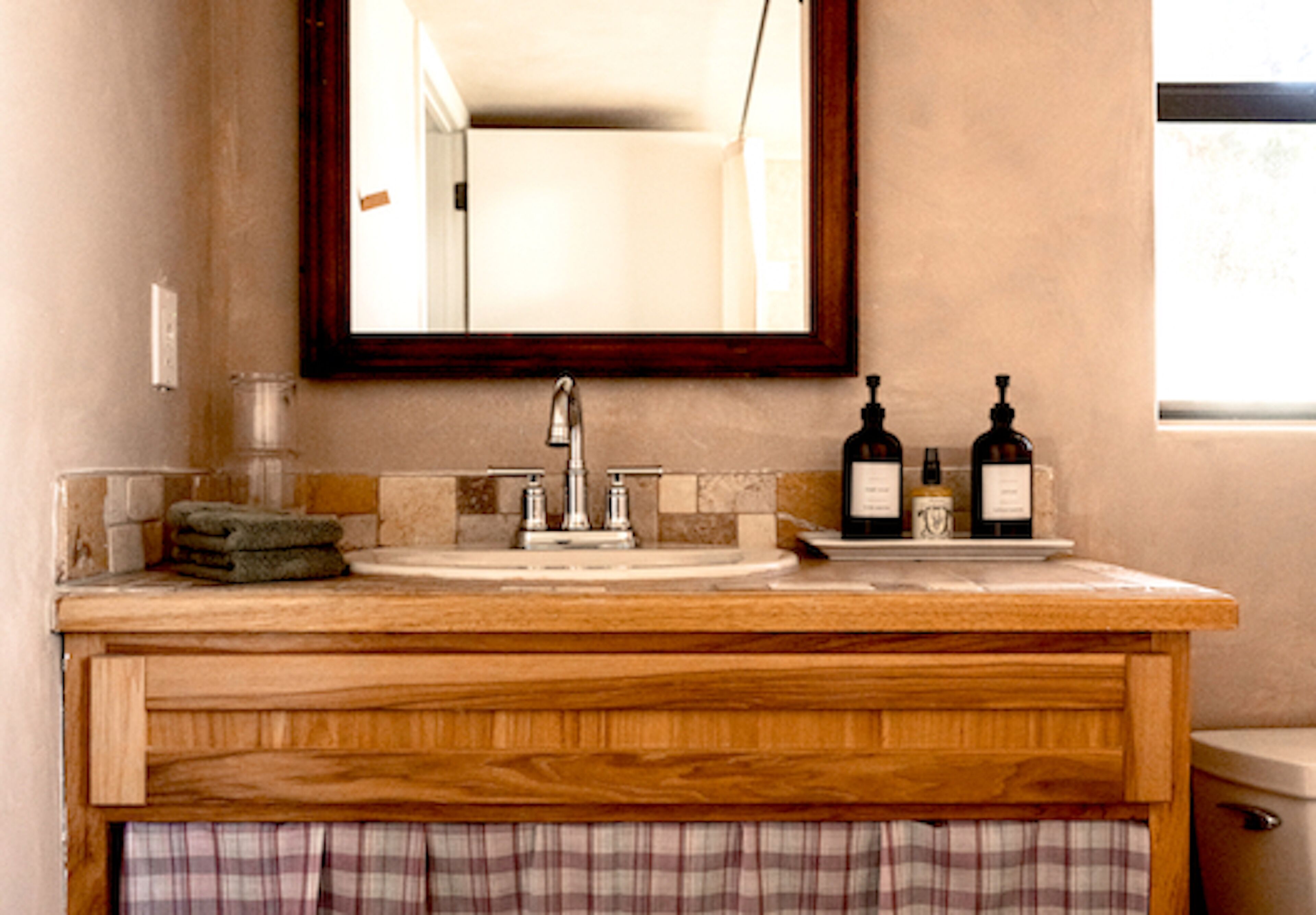A bathroom with a wooden vanity, a sink, and a mirror.