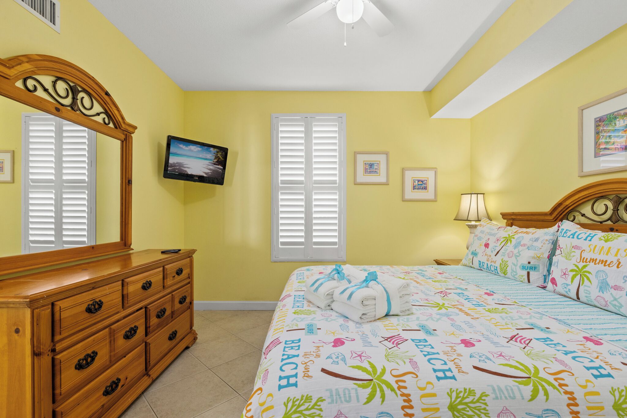 Un dormitorio con cama, cómoda y televisor en la pared.