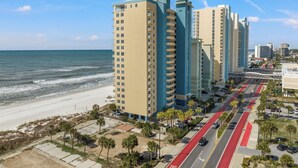 A coastal high-rise building with a beach view, a pedestrian walkway, and a red bike lane. - Grandview Oasis! 3BR 2BA Sleeps 9! Gulf-front Tranquility Beckons! (Panama City Beach)