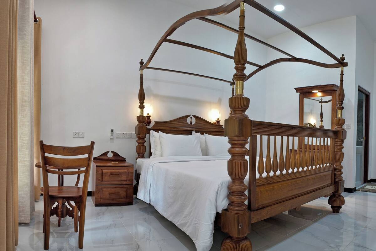 A bedroom with a four-poster bed, wooden furniture, and a large mirror.