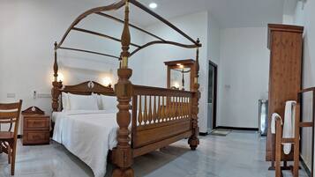 A bedroom with a four-poster bed, wooden furniture, and a large mirror.