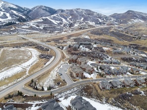 Una zona residencial con una carretera sinuosa, edificios y montañas nevadas al fondo.