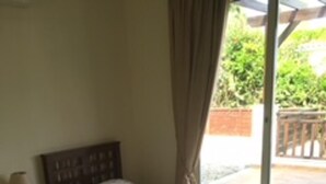 A bedroom with two beds, a nightstand, a lamp, and a window with curtains. - Stunning 3-bed Villa in Peyia (Pegeia)