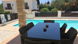 A poolside area with a table and chairs, a lifebuoy, and a pool. - Stunning 3-bed Villa in Peyia (Pegeia)