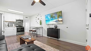 A modern kitchen with white cabinets, stainless steel appliances, and a dining area with a black metal table and stools.