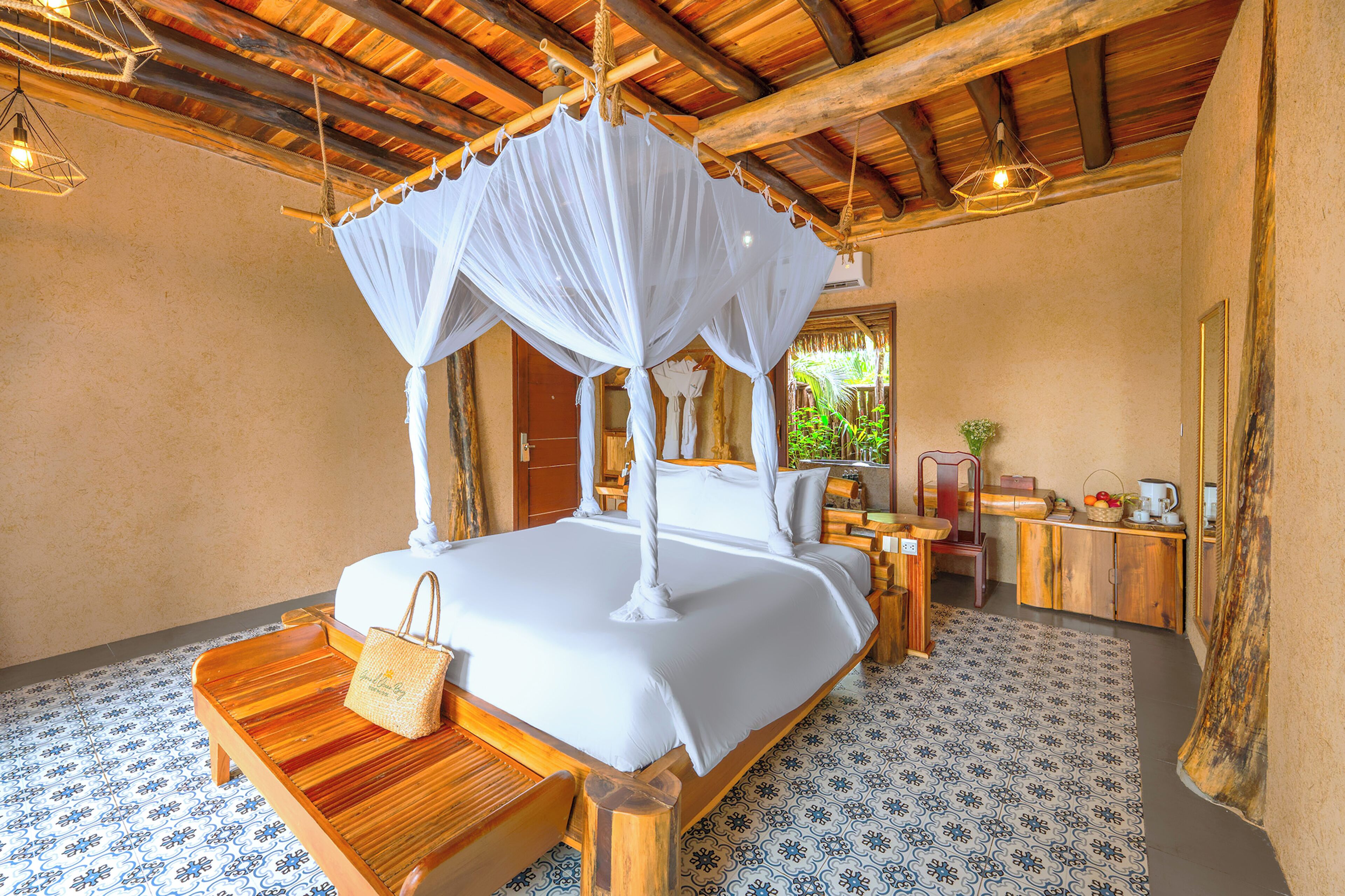 A spacious bedroom with a canopy bed, a wooden bench, and a small table with a handbag.