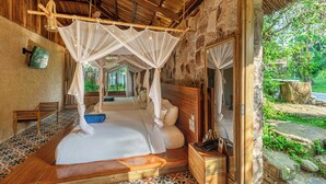 Una habitación con cama, banca de madera y pared de piedra.