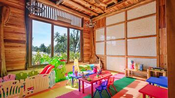 Children can play and explore in this vibrant playroom with a view of palm trees and greenery.