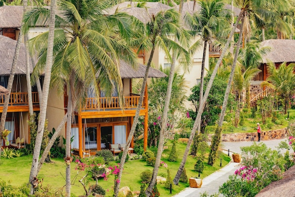 Een resort met rieten bungalows, weelderige tropische tuinen en een helder pad.